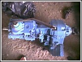 1981 Ford Bronco - A blue transmission assembly with attached hoses and cables is shown resting on the ground.