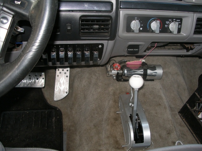 Truck interior with aftermarket shifter, toggle switches, and flame pedal covers
