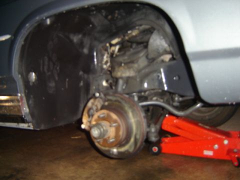 1988 Ford Crown Victoria LTD - Car's front wheel well and suspension are visible, with a red jack underneath.