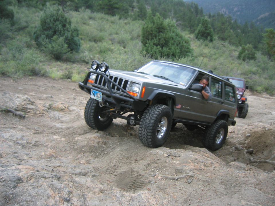 Modified Jeep Cherokee climbing rocks, another Jeep behind it