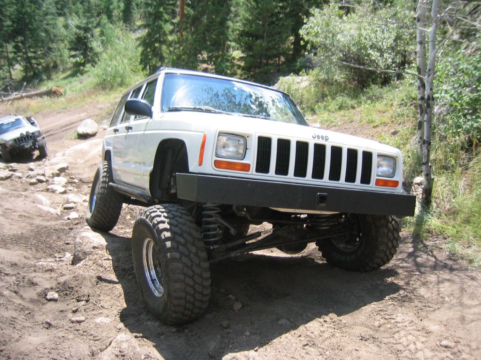 White 1997 Jeep Cherokee on a rocky trail, front 3/4 view