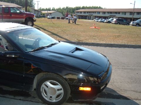 1989 Ford Probe - Front view of a black 1989 Ford Probe parked on a street, with a red pickup truck in the background.