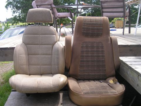 1984 Ford Bronco - Two car seats are displayed outdoors on a wooden deck, with a table and chairs in the background.