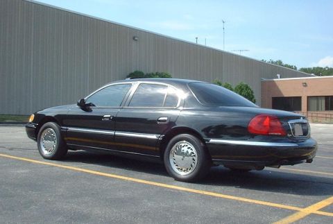 1997 Ford Crown Victoria - A black sedan with chrome accents is parked in a lot, showing its rear three-quarter profile.