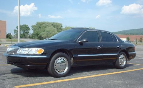 1997 Ford Crown Victoria - A black Lincoln Continental is parked in a lot under a partly cloudy sky.