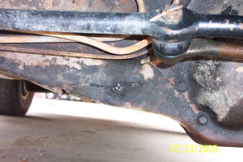 1988 Ford Bronco - Close-up view of rusted and damaged suspension components on the underside of a vehicle.