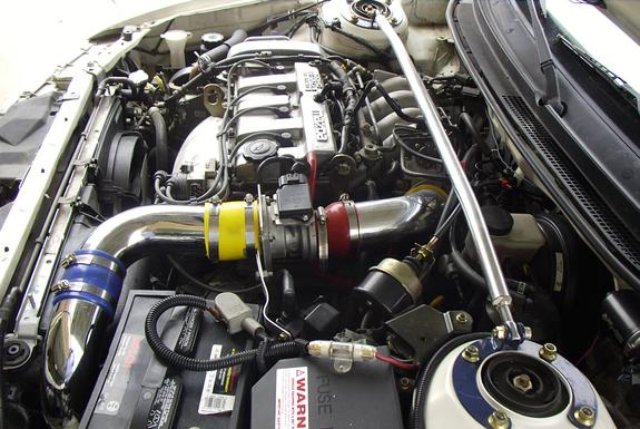 Engine bay with turbocharger, polished intake piping, strut brace and battery