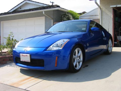 1990 Ford Probe - Blue Nissan 350Z parked in a driveway with a garage in the background.