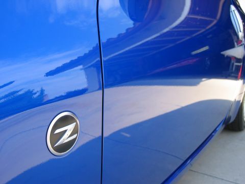 1990 Ford Probe - Close-up of a blue Nissan Z car door, showing the iconic Z emblem and the glossy finish.