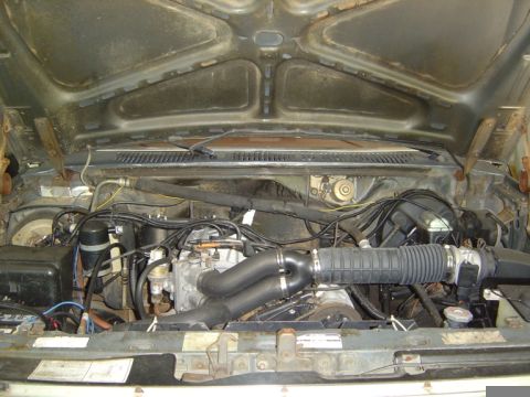 1986 Ford Bronco - The engine bay of a vehicle, showing the engine and associated components under the hood.
