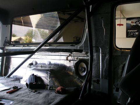 1993 Ford Bronco - The interior of a vehicle shows sound dampening material and a speaker installation, with a roll cage visible.