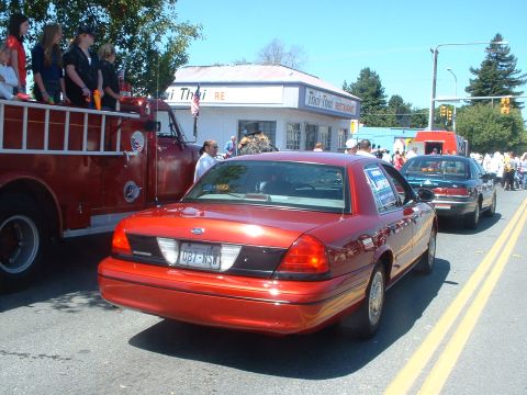 1999 Ford Crown Victoria - A red Ford Crown Victoria is seen in a parade, following a fire truck.