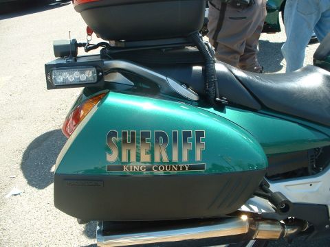 1999 Ford Crown Victoria - Motorcycle marked "SHERIFF KING COUNTY" with a rear storage box and LED light bar.