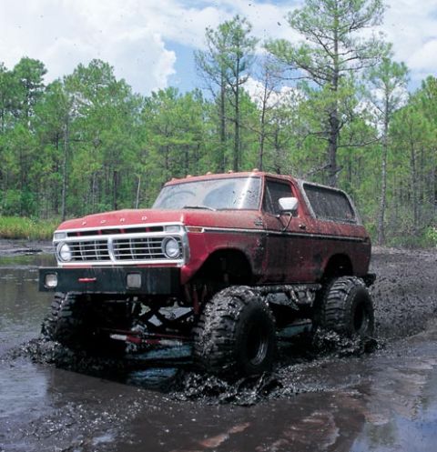 1979 Ford Bronco - This lifted 1978 Ford Bronco is navigating a muddy terrain, kicking up water and mud.