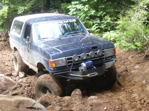 1991 Ford Bronco - This 1991 Ford Bronco tackles a challenging off-road course, demonstrating its capabilities on a steep, muddy incline.