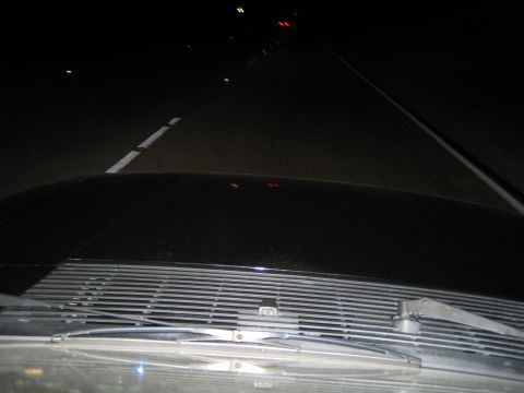 1985 Ford Mustang - View from inside a car at night on a highway, with other vehicles visible in the distance.