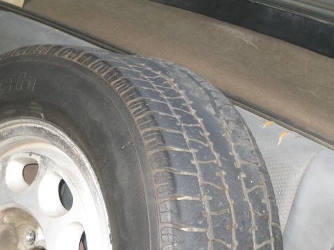 1985 Ford Mustang - A spare tire is visible inside a vehicle, positioned next to a grey interior panel.