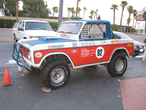 1985 Ford Mustang - A Ford Bronco race truck is parked on asphalt, with palm trees and a motel sign in the background.