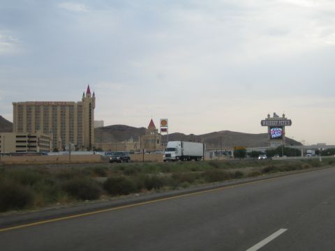 1985 Ford Mustang - A highway passes by Whiskey Pete's casino and a semi-truck drives on the road under a cloudy sky.