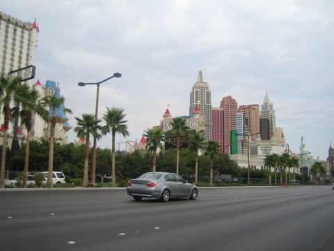 1985 Ford Mustang - A silver sedan drives past the Las Vegas skyline, hotels designed to resemble New York City landmarks.