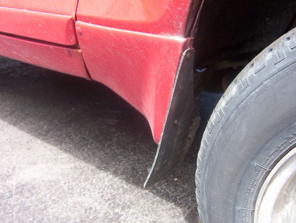 close-up of red vehicle's rear fender, mud flap, and tire