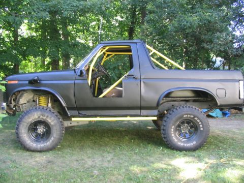 1986 Ford Bronco - This modified Ford Bronco features a yellow roll cage and off-road tires.