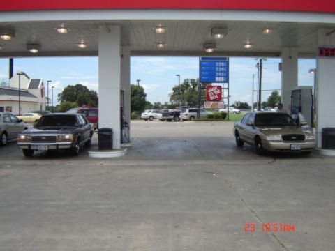 1988 Ford LTD Crown Victoria - A gold Ford Crown Victoria is parked at a gas station, with other vehicles visible in the background.