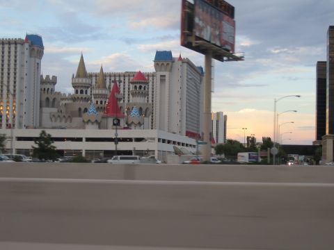 1985 Ford Mustang - A view of the Excalibur Hotel and Casino in Las Vegas, with a billboard and highway traffic visible.