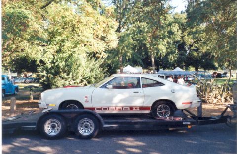 1978 Ford Mustang II - A white 1977 Ford Mustang II Cobra II is transported on a trailer, a distinctive red stripe and badging.