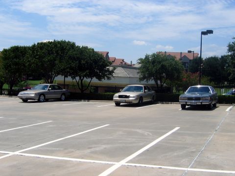 2000 Ford Crown Victoria - Three sedans are parked in a lot on a sunny day with clouds in the sky.