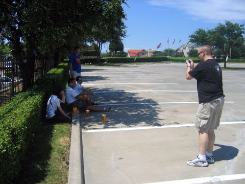 2000 Ford Crown Victoria - People gather in a parking lot on a sunny day, with one person documenting the event with a camera.