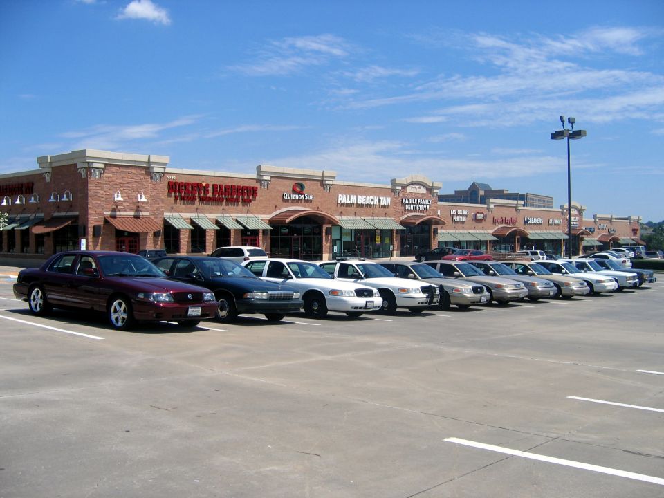 Row of Crown Victoria-style sedans in a strip-mall lot, maroon Marauder in front