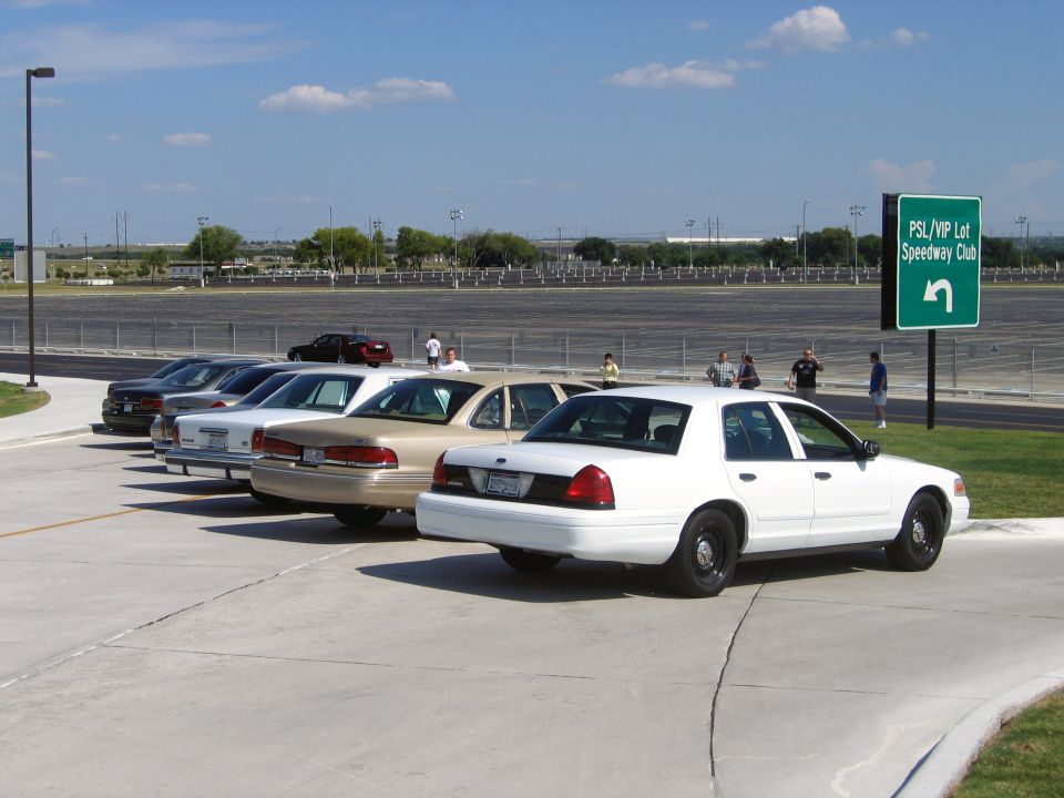 Several police interceptor sedans parked in a lot, one white car in foreground
