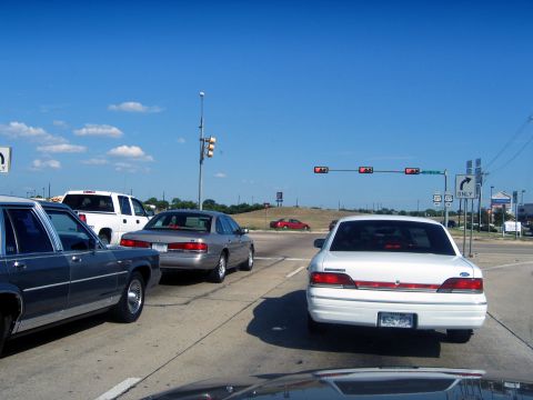2000 Ford Crown Victoria - Several cars are stopped at a traffic light on a sunny day, including a white Ford Crown Victoria.