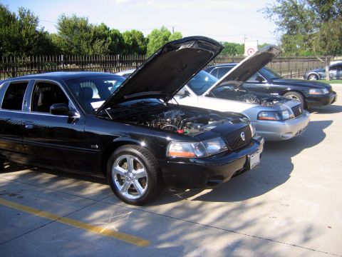 2000 Ford Crown Victoria - Three Ford Crown Victorias are lined up with their hoods open.