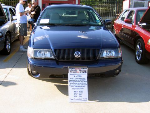 2000 Ford Crown Victoria - A dark blue Mercury Grand Marquis is displayed at a car meet, with a sign providing production statistics.