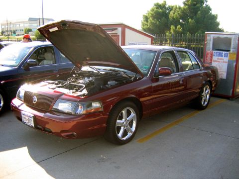 2000 Ford Crown Victoria - A maroon 2000 Ford Crown Victoria is parked with its hood open, revealing the engine compartment.