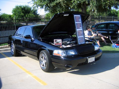 2000 Ford Crown Victoria - Black 2000 Ford Crown Victoria on display with hood open, engine details and information boards.