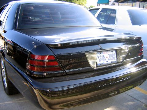 2000 Ford Crown Victoria - This black Mercury Marauder is seen from the rear, parked next to another vehicle.