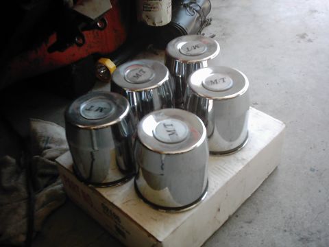 1978 Ford Bronco - Chrome hubcaps with MT branding are arranged on a box.