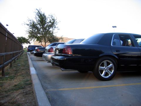 2000 Ford Crown Victoria - Several Ford Crown Victorias are parked in a lot, with the closest one being black and viewed from the rear quarter.