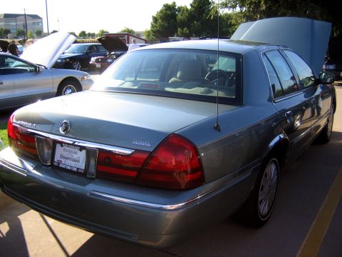 2000 Ford Crown Victoria - A 2000 Ford Crown Victoria is shown from the rear with its hood open, parked at an outdoor event.