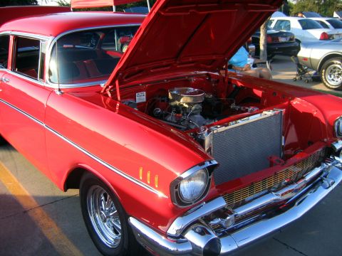 2000 Ford Crown Victoria - A classic red Chevrolet with its hood up at an outdoor car show.