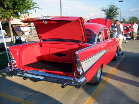 2000 Ford Crown Victoria - A red 1957 Chevrolet Bel Air is displayed with its trunk and hood open at an outdoor car meet.