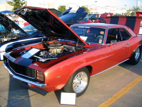 2000 Ford Crown Victoria - Custom 1969 Camaro on display with hood open, racing stripes and aftermarket wheels.