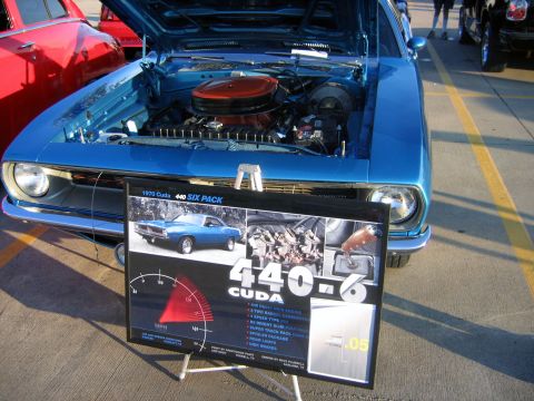 2000 Ford Crown Victoria - A blue 1970 Plymouth Barracuda is displayed with its hood open, alongside a sign detailing its features.