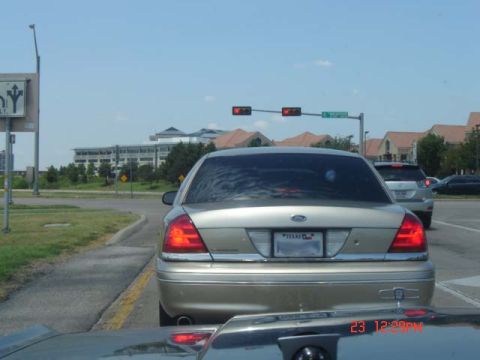 1988 Ford LTD Crown Victoria - This gold Ford Crown Victoria is seen from the rear in traffic, with a Texas license plate visible.
