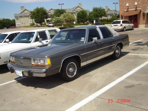 1988 Ford LTD Crown Victoria - A gray 1988 Ford Crown Victoria LTD sedan is parked in a lot next to another white sedan.