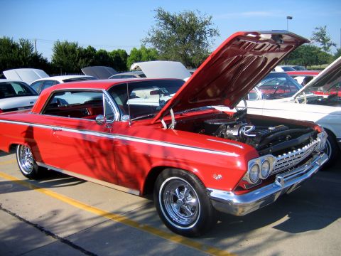 2000 Ford Crown Victoria - Classic red Chevrolet Impala with its hood up at an outdoor car meet.