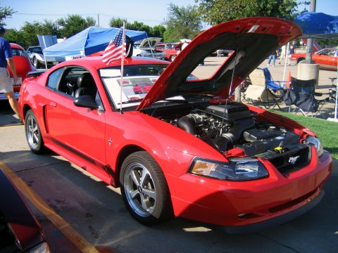 2000 Ford Crown Victoria - A red 2000 Ford Mustang is displayed with its hood open at an outdoor car show.